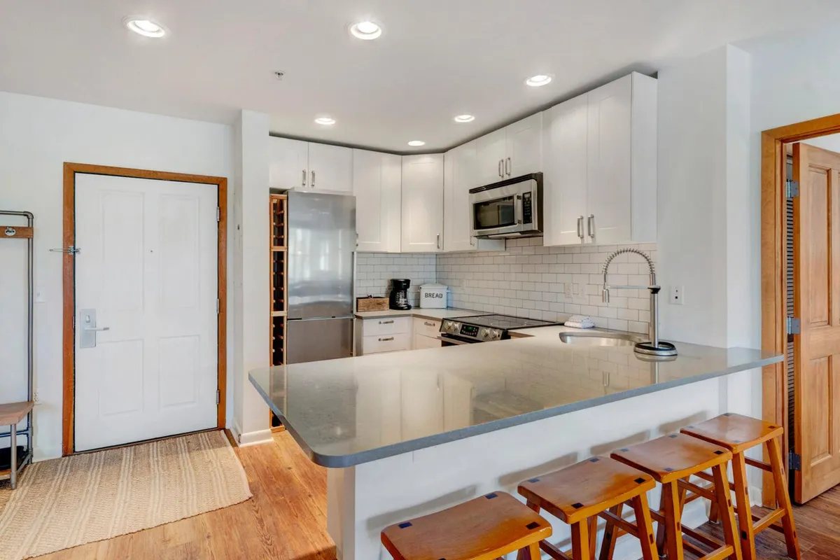 The photo captures a stylish kitchen with a spacious island, modern appliances, and an open concept layout. The environment is welcoming, with room for entertaining, cooking, and casual dining, echoing the communal spirit described in the section.